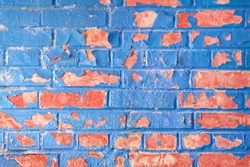 Peeling blue paint on a red brick wall. Blue background.