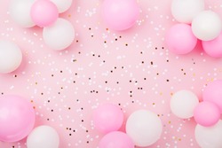 Pastel pink table with frame from balloons and confetti for birthday top view. Flat lay composition.