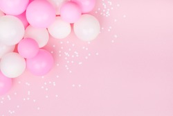 Pastel pink table with colorful balloons and confetti for birthday top view. Flat lay style.