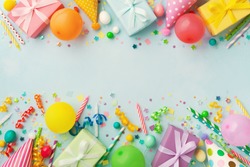 Heap of gift or present boxes, balloons, holiday supplies and confetti on blue table top view. Birthday party background.