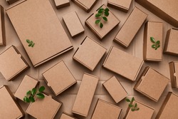 Heap of cardboard boxes from natural recyclable materials with green leaves sprout top view. Responsible consumption, eco friendly packaging, zero waste concept.
