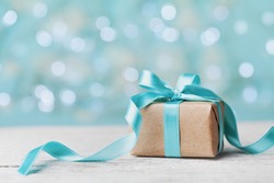 Christmas gift box against turquoise bokeh background. Holiday greeting card.