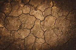 Texture of dry cracked earth. The desert background. The shortage of water on the planet. Deep cracks in the brown land as a symbol of hot climate and drought. Concept of global warming.