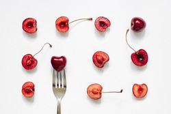 Red cherry fruits and fork on white background. Summer, diet, healthy food eating consept. Top view, flat lay, layout, pattern