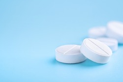 White round pills on blue background. Pharmacy, pharmacology, medicine background with copy space.