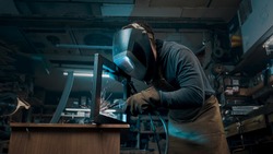 Worker wearing a mask and gloves soldering metal parts