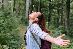 Woman forest bathing with arms outstretched enjoying nature adult caucasian woman in nature practising yoga breathing exercise in forest