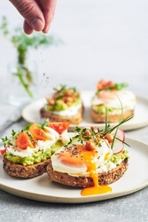 Vegetarian egg sandwiches on white background. Healthy vegetarian sandwiches with egg tomatoes avocado cream and cheese garnished with chia seeds and aromatic herbs. Vegetarian sandwich.