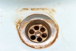 Dirty sink drain mesh, hole with limescale or lime scale and rust on it close up, dirty rusty bathroom washbowl.