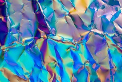 high res full frame macro photo of abstract crumpled iridescent holographic foil background with light leaks. holo color wrinkled material. shiny rainbow color blocking. digital waves.