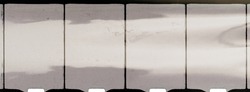 close up of 8mm movie filmstrip isolated on white background with light reflection, old scratched homemovie film material.
