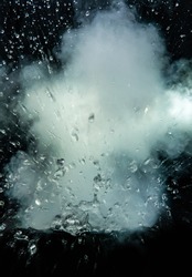 highspeed photo of water explosion with smoke and splashing water drops isolated on black background.