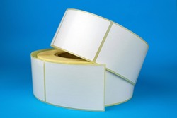 Babina of self-adhesive stickers on a blue background. White roll of labels for thermal perforation Self-adhesive white label roller for printing or manufacturing