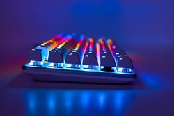 Backlit keyboard. Gaming keyboard with RGB light, side view. Colorful keyboard in neon light, soft focus