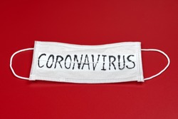 Сoronavirus - COVID-19 - 2019-nCoV, WUHAN virus concept. Surgical mask protective mask with CORONAVIRUS text. Chinese coronavirus COVID-19 outbreak. Red background.