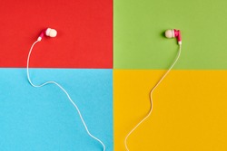 Earphones on colorful background of famous computer corporation, software manufacturer logo. Audio software concept. Red, green, blue, yellow paper colours. Corporation logo.