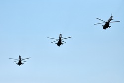 Military helicopters flying in bright blue sky performing demonstration flight, airforce, copy space. Group combat helicopters, aerobatic team performs flight at air show