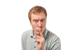 Funny guy in light gray Polo T-shirt asking to be quiet, silence gesture isolated on white background. Young man saying Shhh, keep quiet, please and making silence gesture, request for silence