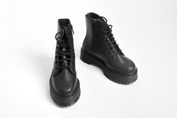 Black women combat boots on high heel platform with lug soles on isolated white background. Military stylish high heel platform combat boots for woman legs, new footwear trends