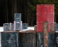 red and blue metal barrels stacked or piled up in field used for paintball court colourful and grungy  grunge background horizontal format room for type wooden slats with paintball paint splatter 