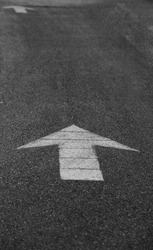 white straight directional arrow painted on pavement asphalt directing away from viewer or to the top of photo space for type direction background backdrop or wallpaper on highway pathway or walkway 