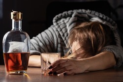 Drunk intoxicated woman sleeping near whiskey glass, female heavy drinker alcoholic passed out lying asleep after booze, alcoholism problem, alcohol addiction concept.