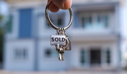 sold house key and blurry home on background