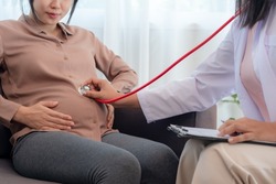 Gynecologist with stethoscope listens to baby's heartbeat in pregnant woman. Pregnancy, gynecology, medicine, health care, doctor, health check up during pregnancy. 