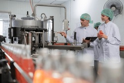 A quality supervisor or food or beverages technician discuss about process control of food and drugs before send product to the customer. Production leader recheck ingredient and productivity.