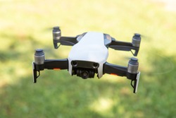 Flying drone with video camera with blurred green background