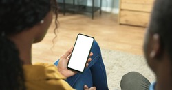 Close up of African American couple man and woman sitting in room surfing on smartphone with blank screen in woman hands. Mobile phone with blank copy space screen for your text