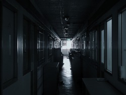 Corridor of the old and dark dormitory with window light.