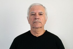 old male senior black shirt closeup white wall background sad unhappy depression face expression frowning looking no emotion retired