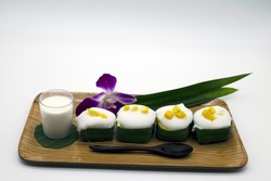 Thai dessert menu named Taco dessert Topped with sweet coconut milk in a wooden tray and pandan leaves. Clipping Path included.