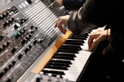 Playing music on the keyboard of a modern analog synthesizer. Selective focus.