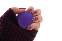 Hand in violet sweater with violet manicure with jewelery box on white background.