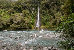 Thunder Creek Falls in Mt Aspiring National Park, with the Haast River in the foreground. Mt Aspiring National Park, West Coast, New Zealand.