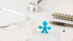 Family healthcare, medicine and insurance concept. Family figure, cardiograms, pen with notepad and stethoscope on a white doctor desk. Medical worktable. Soft image and soft focus style