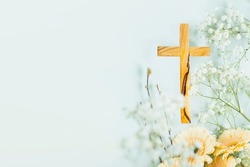 Wooden cross with spring flowers on blue background with copy space. Religion background. Religious church holidays. Christianity Feast, Easter, Palm Sunday, Christening, church wedding. Flat lay