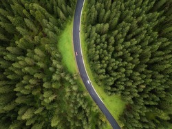 Aerial view of road and  cars passing by in green forest in mountains. drone shot