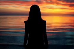 silhouette of young beautiful girl on sunset tropical beach. natural summer background