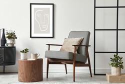 Stylish scandinavian composition of living room with design armchair, black mock up poster frame, commode, wooden stool, book, decoration, loft wall and personal accessories in modern home decor.