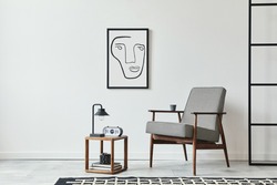 Stylish scandinavian composition of living room with design armchair, black mock up poster frame, carpet decor, wooden stool, clock, decoration, loft wall and personal accessories in modern home decor
