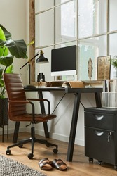 Stylish interior design composition of modern masculine home office with black industrial desk, brown leather armchair, pc and stylish personal accessories. Template.