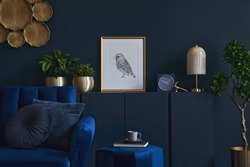 Creative composition of glamour living room interior design with mockup poster frame, wooden commode, lamp and elegant personal accessories. Dark blue wall. Home staging. Template. Copy space.