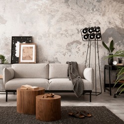 Interior design of industrial living room interior with mock up poster frame, gray sofa, round wooden coffee table, brown leather armchair, black desk, modern lamp, accessories. Home decor. Template.
