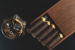 Cigars sticking out of a wooden box and a glass of whiskey with ice