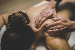 Soft focus view of man massaging a woman in a wellness center Oiled hands on a body relaxing the muscles and relieve tension  Holistic exercise for calm and clear your mind. Health well-being concept