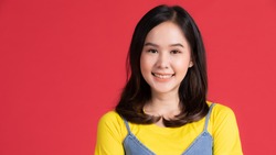 Portrait of young and beautiful and cheerful Asian girl pose with friendly face and cute smile to camera and self-confidence on red background