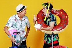 Asian man surprised and thrilled with jellyfish toy in hand while friend playing ring float and snorkel also wondering. Two brothers going on summer vacation on beach for scuba diving, swimming.